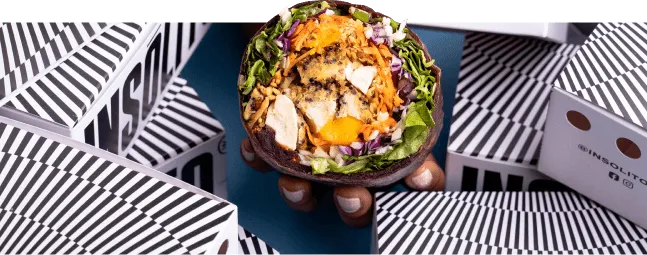 Bowl de Insólito sostenido con una mano, entre cajas de la marca
